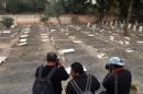 Pakistani news photographers take pictures of desecrated graves at the minority Ahmadi sect graveyard in Lahore on December 3, 2012
