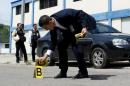 A criminal investigator collects evidence in the area where a woman was shot when looters raided state food warehouses, in San Cristobal