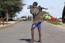 Somali government soldiers walk near the scene of a suicide car bomb explosion targeting peacekeeping troops in a convoy outside the capital Mogadishu