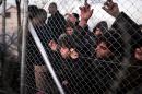 Refugees look through a fence towards the Macedonian side at the Greek-Macedonian border near the village of Idomeni on March 1, 2016