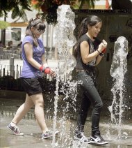 Dos jóvenes juegan en una fuente de la capital tinerfeña para mitigar las altas temperaturas que se registran en el Archipiélago. EFE/Archivo