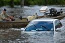 A man navigates a boat of rescued goats past a partially submerged car after flooding on August 16, 2016 in Gonzales, Louisiana