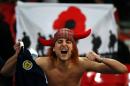 A Scottish supporter sings in front of a flag with a poppy symbol to represent the war dead before a World Cup 2018 qualification match between England and Scotland at Wembley stadium in London on November 11, 2016