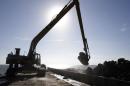 A large excavator is silhouetted as it scoops up a load of limestone boulders from a barge in the gulf of Mexico off the Texas coast on Tuesday, Oct. 29, 2013. The huge boulders will be dropped into the water to help rebuild a reef that once filled some 400 acres and now barely exists. (AP Photo/Pat Sullivan)