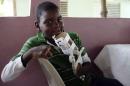 Handicapped Haitian boy Stevenson Joseph holds the 3D-printed prosthetic hand that he is learning to use in Santo