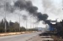 Smoke rises near a damaged road in Dahiyet al-Assad, west Aleppo city