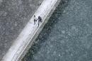 Joggers run along the embankment of Aare river during the first snowfall in Bern