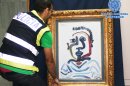 In this photo released by the Spanish Police a police officer holds a forged Pablo Picasso oil painting in Sevilla, Spain, Saturday, July 7, 2012. The Interior Ministry says National Police have arrested four people for trying to sell a forged Pablo Picasso oil painting for up to 1.2 million euros ($1.5 million). The canvas, a counterfeit version of a 1964 work called “The bust of Jeune Garcon” was accompanied by false authenticity documents bearing the signatures of Paloma, one of the Spanish painter’s daughters, and a renowned French art expert. (AP Photo/Spanish Police)