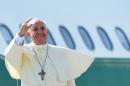 Pope Francis waves from the top of the stairs leading to the plane that will carry him to the South Korea, on August 13, 2014 at Rome's Fiumicino international airport