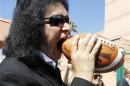 Musician Gene Simmons of rock band KISS bites a football after a news conference to announce his part-ownership of Arena Football League team, the Los Angeles Kiss, in Anaheim