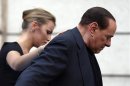 Former Italian Prime Minister Silvio Berlusconi leaves the stage flanked by his girlfriend Francesca Pascale at the end of a rally to protest his tax fraud conviction, outside his palace in central Rome