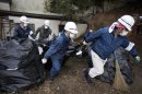 In this Wednesday, March 6, 2013 photo, workers haul a bag of radiation-contaminated leaves during a cleanup operation in the abandoned town of Naraha, just outside the exclusion zone surrounding the Fukushima Dai-ichi nuclear plant in Japan. Two years after the triple calamities of earthquake, tsunami and nuclear disaster ravaged Japan's northeastern Pacific coast, radioactive and chemical contamination remains a threat. (AP Photo/Greg Baker)