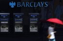 A woman walks past a line of Barclays cash dispensers in central London