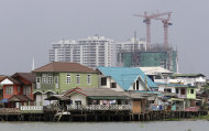 FILE - In this March 26, 2012 file photo, residences on stilts sit along the Chao Phraya River with a construction site in the background in Bangkok, Thailand. Sea level rise projections show Bangkok could be at risk of inundation in 100 years unless preventive measures are taken. (AP Photo/Sakchai Lalit, File)