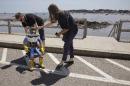 HitchBOT co-creator David Harris Smith adjusts its position as co-creator Frauke Zeller, right, says farewell as the hitchhiking robot starts its journey Friday, July 17, 2015, in Marblehead, Mass. HitchBOT is beginning its' first cross-country hitchhiking trip of the U.S., in Marblehead with a final destination goal of reaching San Francisco. (AP Photo/Stephan Savoia)