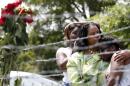 Area residents Alberta Harris, center, and Waynetta Theodore, left, and Christiena Preston, console each other as they pay their respects at a makeshift memorial, near the site where two Mississippi police officers were killed, Sunday, May 10, 2015, in Hattiesburg, Miss. The officers were shot to death during an evening traffic stop turned violent, a state law enforcement spokesman said Sunday. Three suspects were in custody, including two who are charged with capital murder. (AP Photo/Rogelio V. Solis)