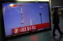 A passenger walks past a TV screen broadcasting the news that the launch of Korea Space Launch Vehicle-1 (KSLV-1), or Naro, was cancelled due to a problem in the upper second-stage rocket, at a railway station in Seoul