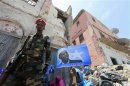 A government soldier walks past a woman holding a campaign poster of Somalia's President Sheikh Sharif Ahmed in Mogadishu
