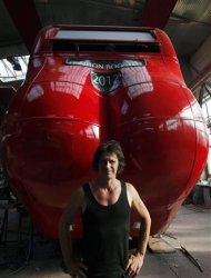 Czech artist David Cerny poses next to a London bus that he has transformed into a robotic sculpture in Prague July 2, 2012. The bus, which Cerny hopes could become an unofficial mascot of the London 2012 Olympic Games, does push-ups with the help of an engine powering a pair of robotic arms, and the motion is accompanied by a recording of sounds evoking tough physical effort. It will be parked outside the Czech Olympic headquarters in London for the duration of the Games. Picture taken July 2, 2012. REUTERS/Petr Josek