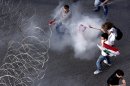 Lebanese protesters are enveloped in tear gas as they pull a barbed-wire barrier during clashes after the funeral of Brig. Gen. Wissam al-Hassan who was assassinated on Friday by a car bomb in Beirut, Lebanon, Sunday Oct. 21, 2012. Lebanese soldiers fired guns and tear gas to push back hundreds of protesters who broke through a police cordon and tried to storm the government headquarters in Beirut. The enraged crowd came from the funeral of a top Lebanese intelligence official assassinated in a massive car bombing.(AP Photo/Hussein Malla)