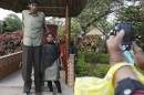 File photo of a visitor posing with Gattaiah, who claims to be the tallest man in India, at the arts and crafts centre in the southern Indian city of Hyderabad