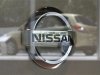 Nissan Motor Corp's logo is pictured as a Nissan vehicle is reflected on glass at the Nissan Gallery in Yokohama