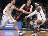 Toronto Raptors Andrea Bargnani tries to pass between Brooklyn Nets Brook Lopez and Gerald Wallace in NBA game in New York