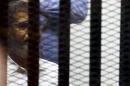 Ousted Egyptian President Mohamed Mursi looks on from behind bars, along with other Muslim Brotherhood members at a court in the outskirts of Cairo