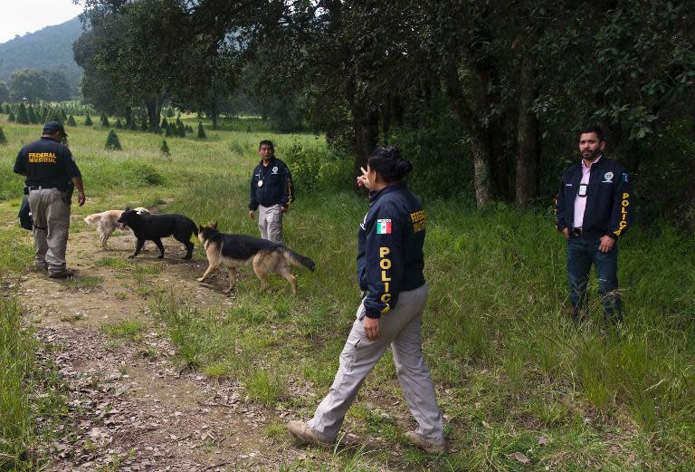 This file photo shows Mexican police officers searching for evidence in the municipality of Tlalmanalco, southeast of Mexico City, on August 22, 2013, after bodies were discovered in a mass grave