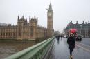 A woman walks across Westminster Bridge past the Houses of Parliament during a snow flurry in London on January 13, 2017