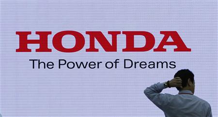 A man is silhouetted against a logo of Honda Motor at the company showroom in Tokyo in this October 23, 2012, file photo. Honda Motor Co will recall 871,000 vehicles that could roll away after the ignition key has been removed, including 807,000 in the United States, the company said on December 12, 2012. The automaker said a part in the ignition interlock could become damaged or worn, enabling the key to be removed even if the vehicle's transmission lever has not been shifted into park. REUTERS/Toru Hanai/Files