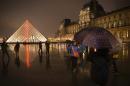 Chinese tourists take at night photos of each other outside the main entrance to the Louvre museum and its pyramid, on March 24, 2015 in Paris