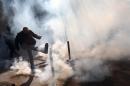 A masked protestor kicks a tear gas canister during clashes with riot police as part of the traditional May Day march in Paris, France, Sunday, May 1, 2016. The traditional May Day rallies are taking on greater weight this year in France as Parliament is debating a bill that would allow longer working hours and let companies lay workers off more easily. (AP Photo/Michel Spingler)