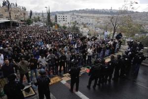 Palestinians pray as Israeli police officers stand …