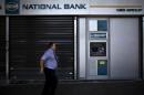 A man walks past an ATM of a National Bank branch in Athens on July 19, 2015