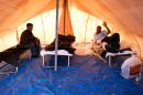 Migrants who were rescued off Cyprus the previous evening sit in a tent at Kokkinotrimithia refugee camp on November 4, 2015