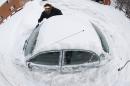 AP10ThingsToSee - In an image made with a fisheye lens, Marguerite Johnston uncovers her car in Grosse Pointe, Mich., Monday, Jan. 6, 2014. The United States experienced historic low temperatures this week due to the polar vortex. (AP Photo/Paul Sancya, File)