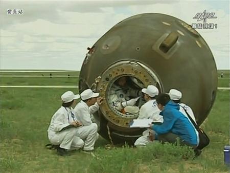 Ground crew talks to astronaut Nie Haisheng before helping him out of the re-entry capsule of China's Shenzhou-10 spacecraft after it landed at its main landing site in north China's Inner Mongolia Autonomous Region in this still image taken from a video, June 26, 2013. REUTERS/CCTV via REUTERS TV