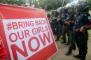 Supporters of the #BringBackOurGirls campaign hold a sign as policewomen block supporters of the 219 Chibok schoolgirls kidnapped by Boko Haram militants from marching to the president's official residence in Abuja on October 14, 2014