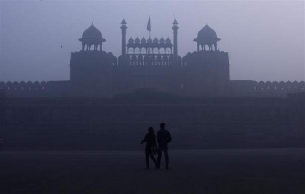 Pasangan berjalan di depan Red Fort yang bersejarah di tengah kabut dan pagi yang dingin di kota tua Delhi, 3 Januari 2012.