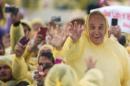 Pope Francis (R) wears a plastic poncho as he waves to well wishers after a mass in Tacloban on January 17, 2015