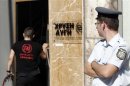 Greek police officer watches as a member of the Golden Dawn far-right party enters the party's headquarters in Athens