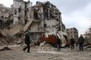 Syrians walk along a destroyed street in the old city of Aleppo on December 17, 2016, as pro-government forces re-open roads that were barricaded to divide rebel and government-held areas