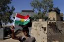 A Kurdish Peshmerga fighter waves a Kurdish flag at a combat outpost on the outskirts of Makhmour, 300 kilometers (186 miles) north of Baghdad, Iraq, Saturday, Sept. 6, 2014. The U.S. and nine key allies agreed Friday, that the Islamic State group is a significant threat to NATO countries and that they will take on the militants by squeezing their financial resources and going after them with military might. (AP Photo/ Marko Drobnjakovic)