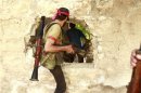 Free Syrian Army fighters move through a hole in a wall in the northern town of Khan al-Assal, after seizing it