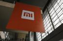 People stand near a logo of Xiaomi ahead of the launching ceremony of Xiaomi Phone 4, in Beijing