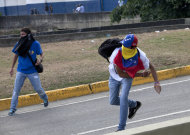 Manifestantes lanzan piedras contra la policía antidisturbios en medio de enfrentamientos entre opositores y estudiantes con las autoridades que dispersaron una protesta que bloqueaba una autopista en el barrio de Altamira, Caracas, Venezuela, el lunes 15 de abril del 2013. Las tropas de la Guardia Nacional dispersaron a quienes protestaban por los resultados de la elección presidencial especial del domingo, cuyos estrechos resultados a favor del oficialista Nicolás Maduro fueron rechazados por el candidato opositor Henrique Capriles, quien demandó un conteo de todos los votos. (AP Foto/Ramon Espinosa)