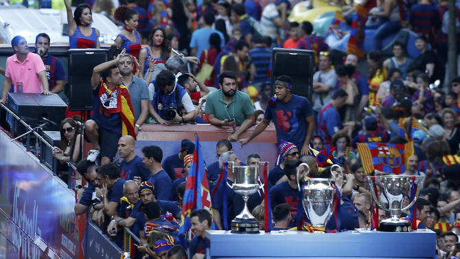 Barcelona&#39;s Xavi Hernandez, top left, waves to fans fron a team bus during celebrations in Barcelona, Spain Sunday June 7, 2015 after winning the Champions League final soccer match Saturday by beating Juventus Turin 3-1. Barcelona won the triple this season winning the Spanish League title, the Copa del Rey and the Champions League. (AP Photo/Manu Fernandez)