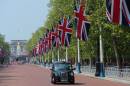 Union Flags fly along The Mall as a taxi passes near the Queen Victoria Memorial statue and Buckingham Palace in London, on May 29, 2012