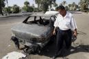 FILE - This Sept. 25, 2007 file photo shows an Iraqi traffic policeman inspecting a car destroyed by a Blackwater security detail in al-Nisoor Square in Baghdad, Iraq. A former Blackwater security guard says he decided to tell the truth about his role in the shooting of 32 Iraqi civilians in a Baghdad square because he wants to move on with his life, even though it might mean he probably will go to prison. Jeremy Ridgeway is testifying against four of his former colleagues who would face long prison terms if convicted of killing 14 Iraqis and wounding 18 others in Nisoor Square. Ridgeway is the prosecution's chief cooperating witness in the case focusing on events that happened seven years ago. He has pleaded guilty to voluntary manslaughter and attempted manslaughter. The trial has been underway for more than one month. (AP Photo/Khalid Mohammed, File)